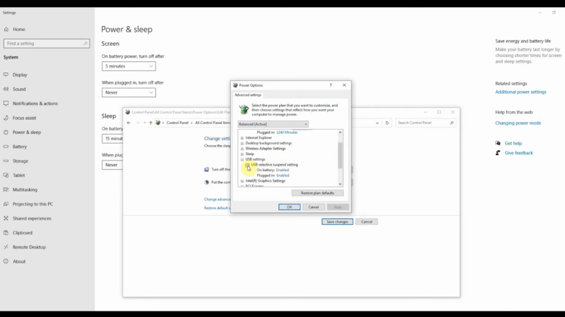 The image shows the "Power & Sleep" settings in Windows, with the "Power Options" window open in the foreground, highlighting the USB selective suspend setting options under "USB settings" for both "On battery" and "Plugged in"