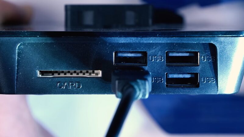 The Image Shows a Close-Up of A Device Featuring Several USB Ports and A Card Slot, with One USB Port Actively in Use, Indicated by A Connected USB Cable